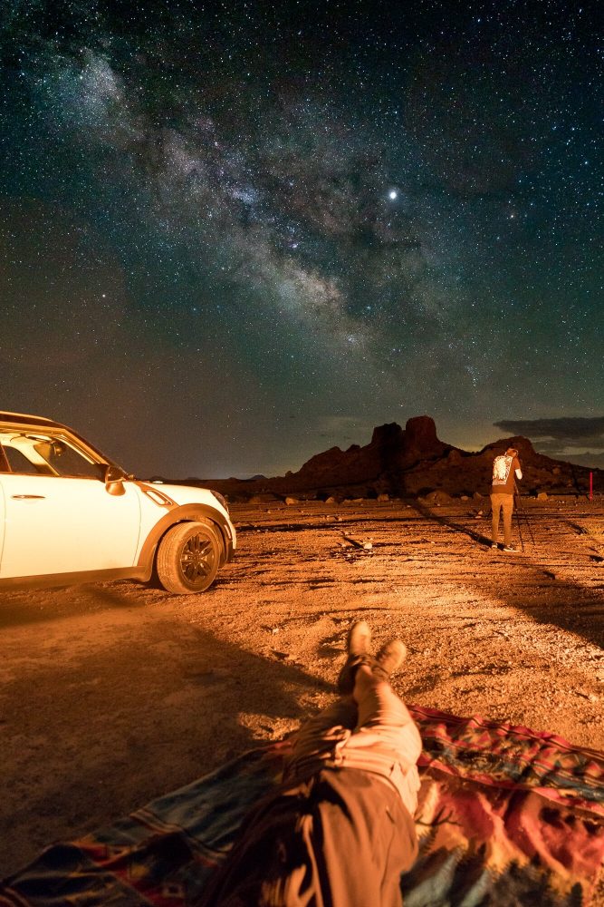 astrophotography long exposure of me laying on the ground while tyler minney shoots the milky way at trona pinnacles | photo by jake landon schwartz